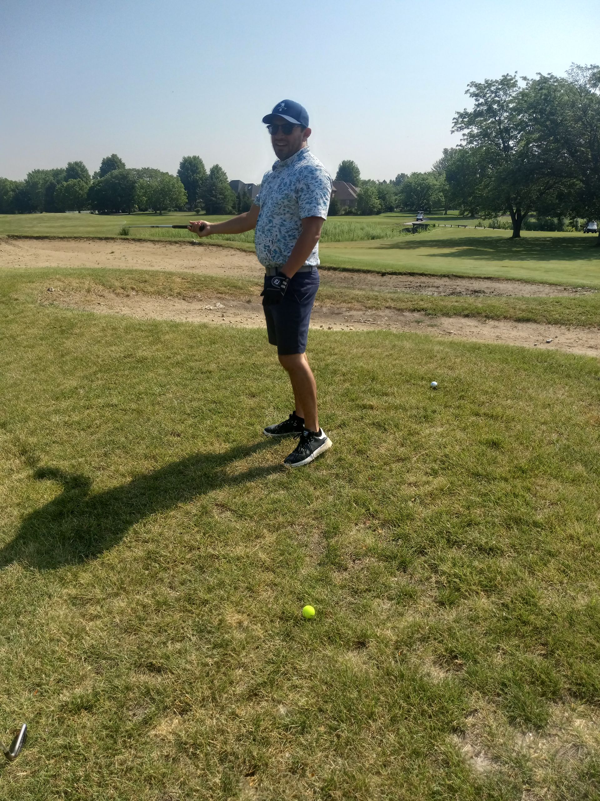A man is standing on a golf course holding a golf club.