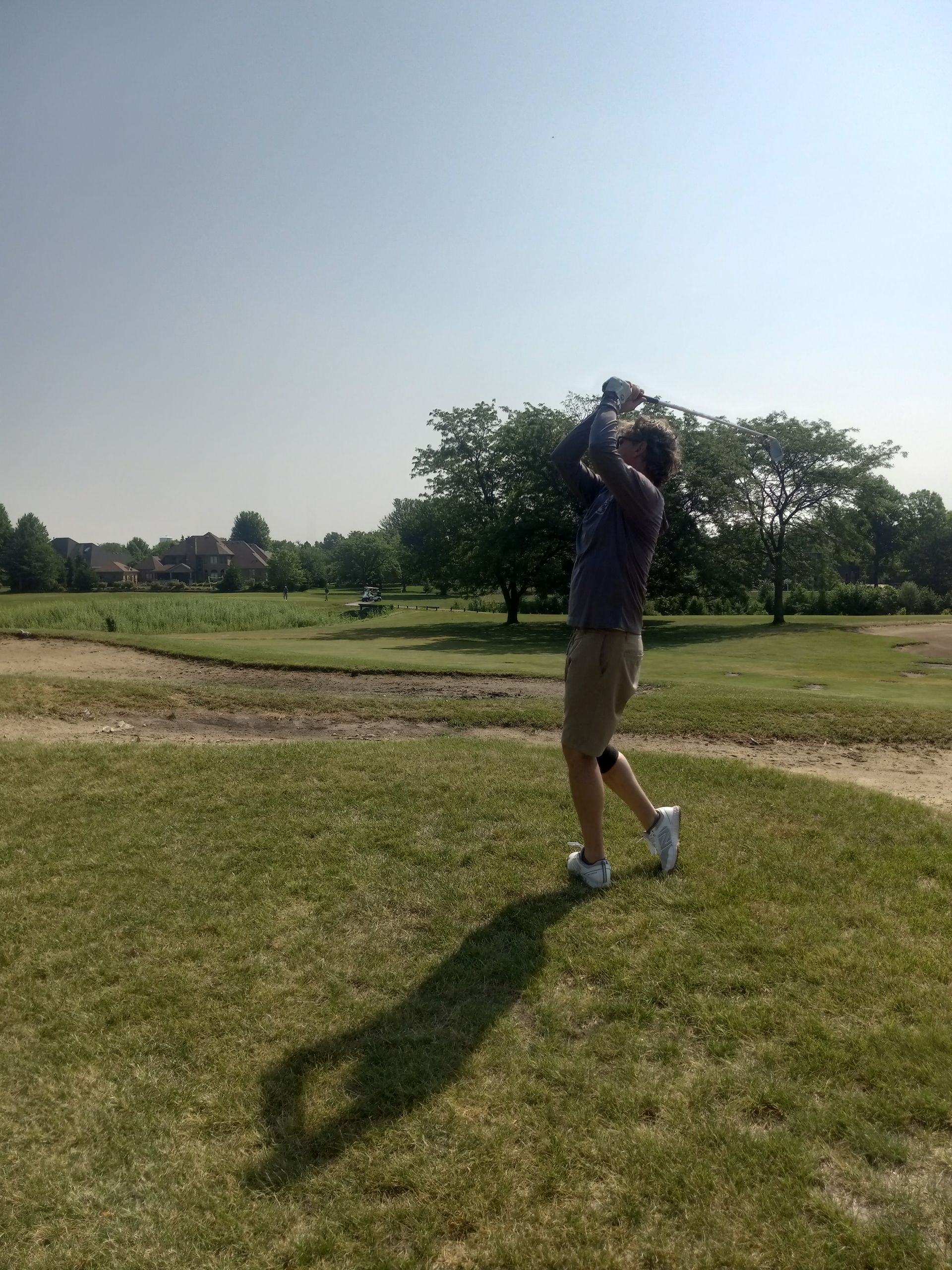 A man is swinging a golf club on a golf course