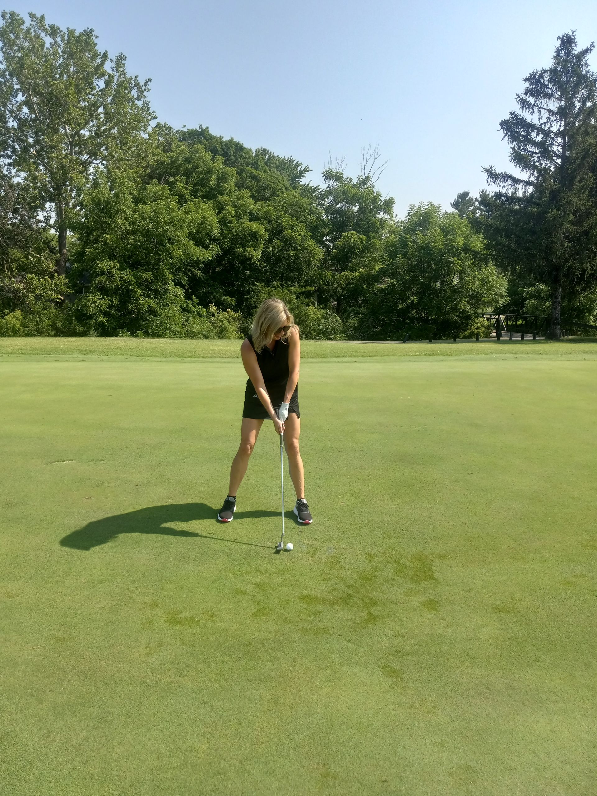 A woman is swinging a golf club on a golf course