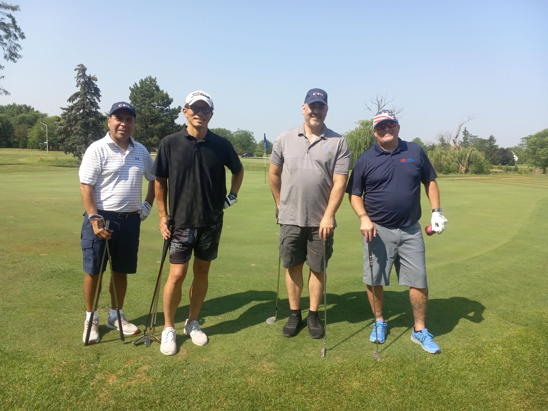 A group of men are standing on a golf course holding golf clubs.