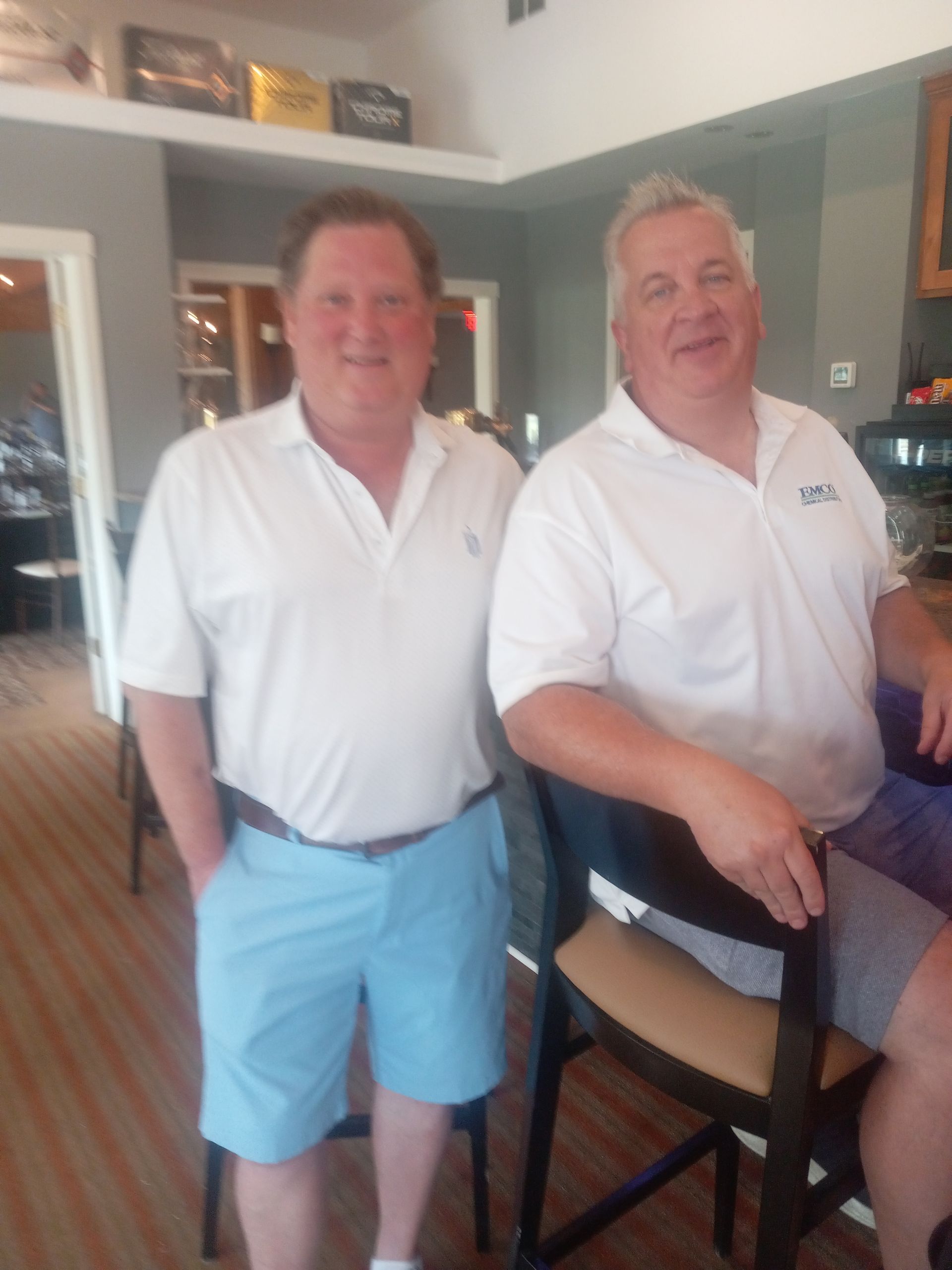 Two men standing next to each other with one wearing a shirt that says tbc