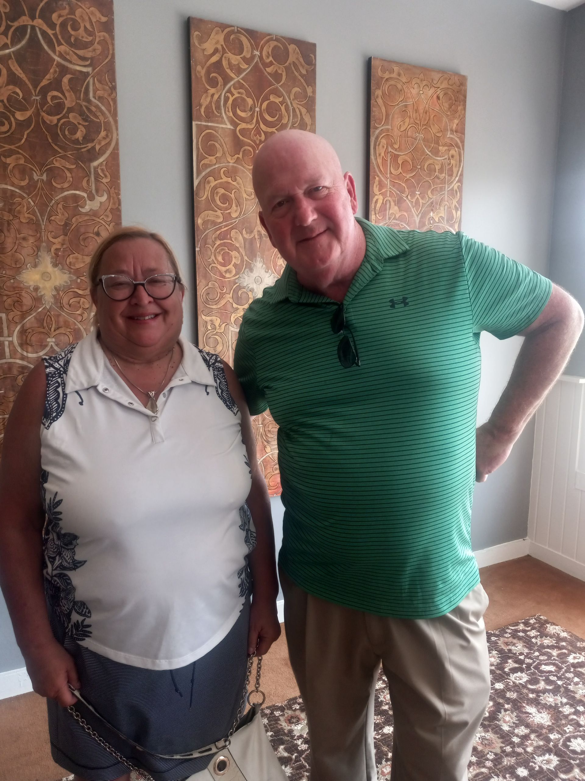 A man in a green shirt stands next to a woman in a white shirt
