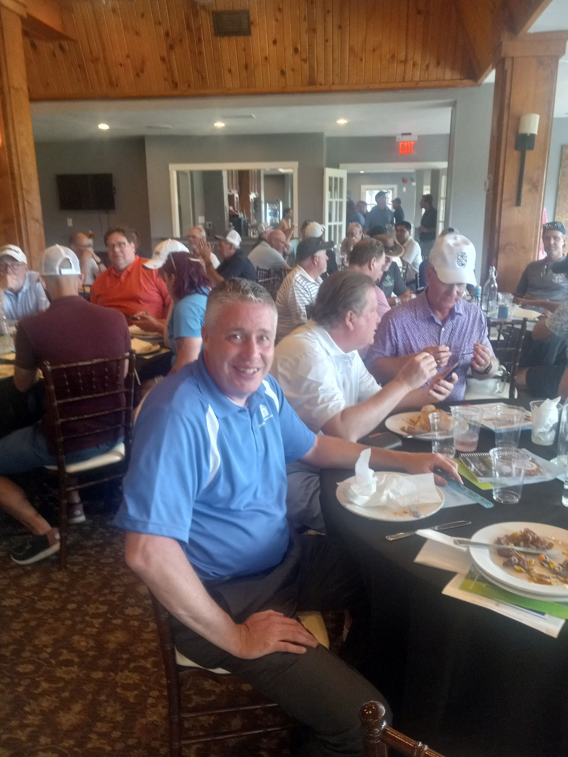 A man in a blue shirt is sitting at a table with other people