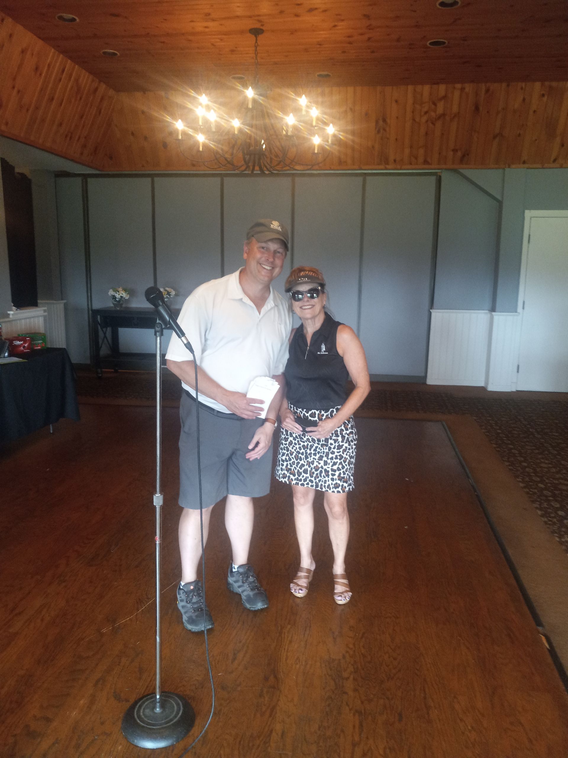 A man and a woman are standing in front of a microphone in a room.