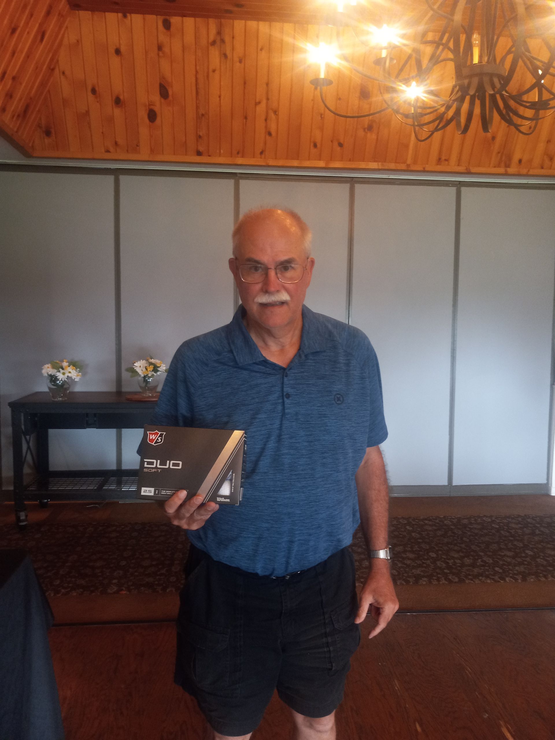 A man in a blue shirt is holding a book in a room