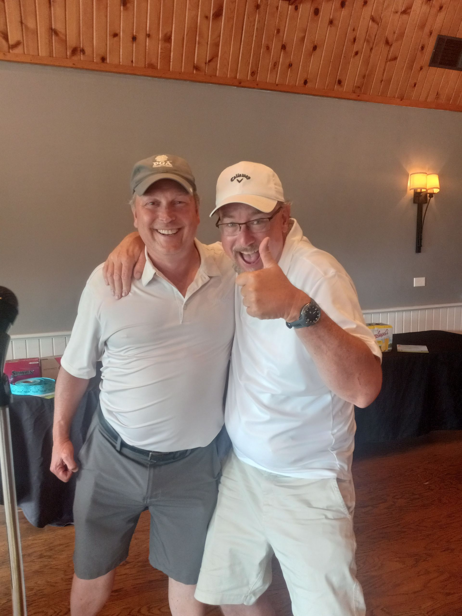 Two men are posing for a picture and one is giving a thumbs up