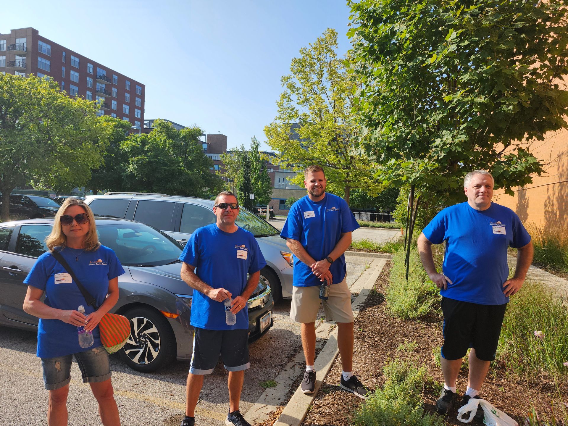A group of people in blue shirts are standing in a parking lot.