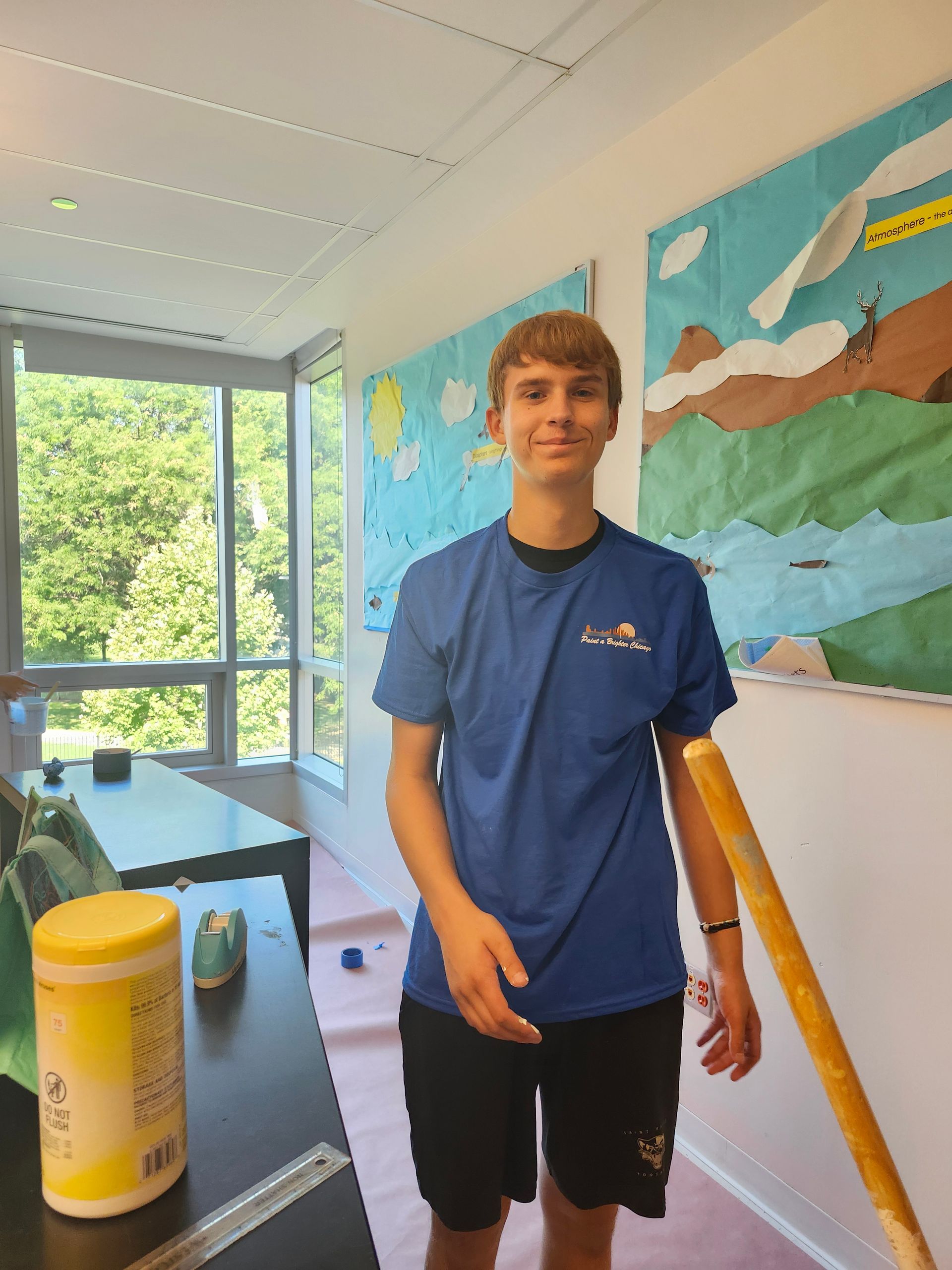 A boy in a blue shirt is standing in front of a painting
