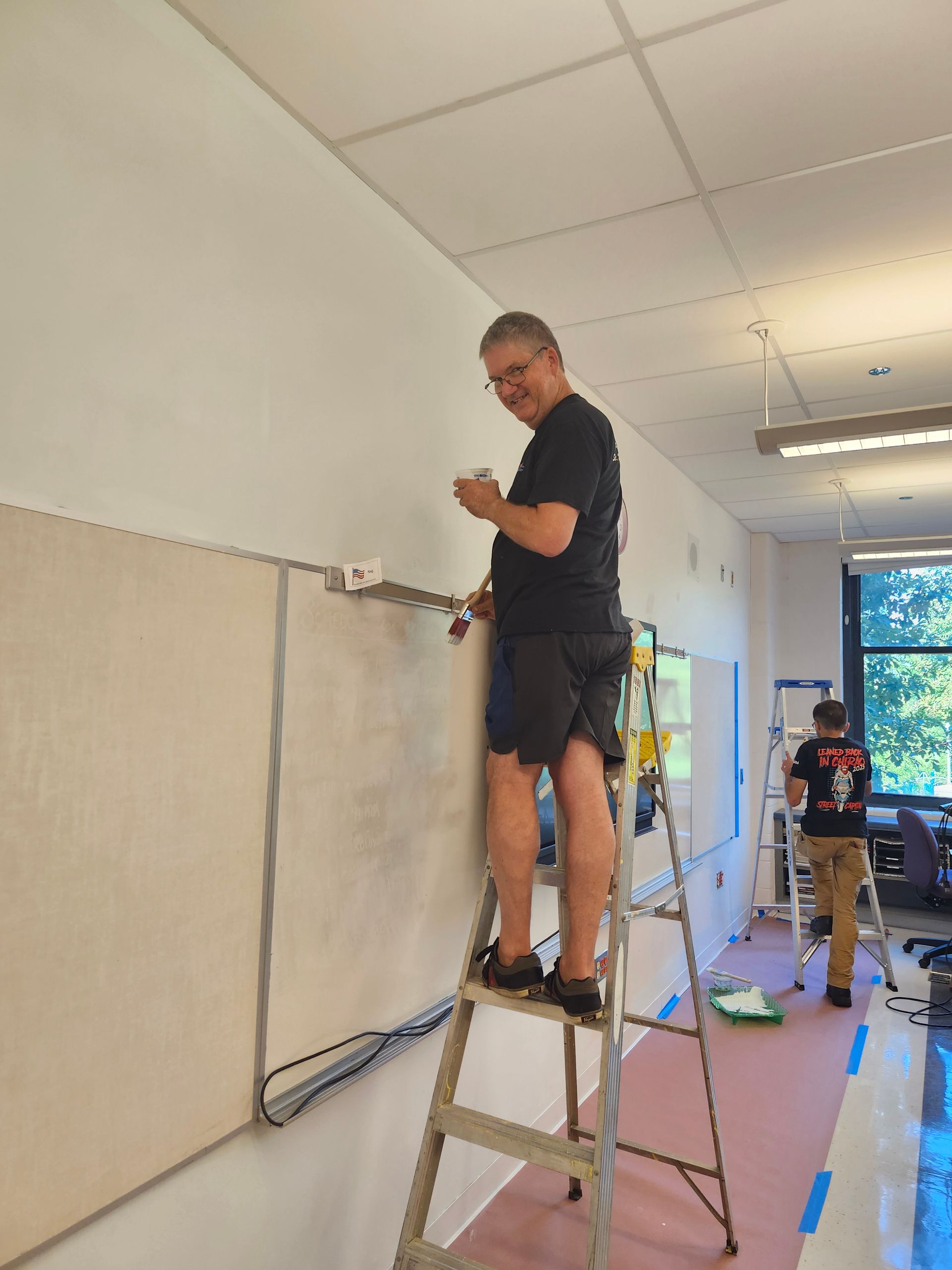 A man standing on a ladder working on a wall
