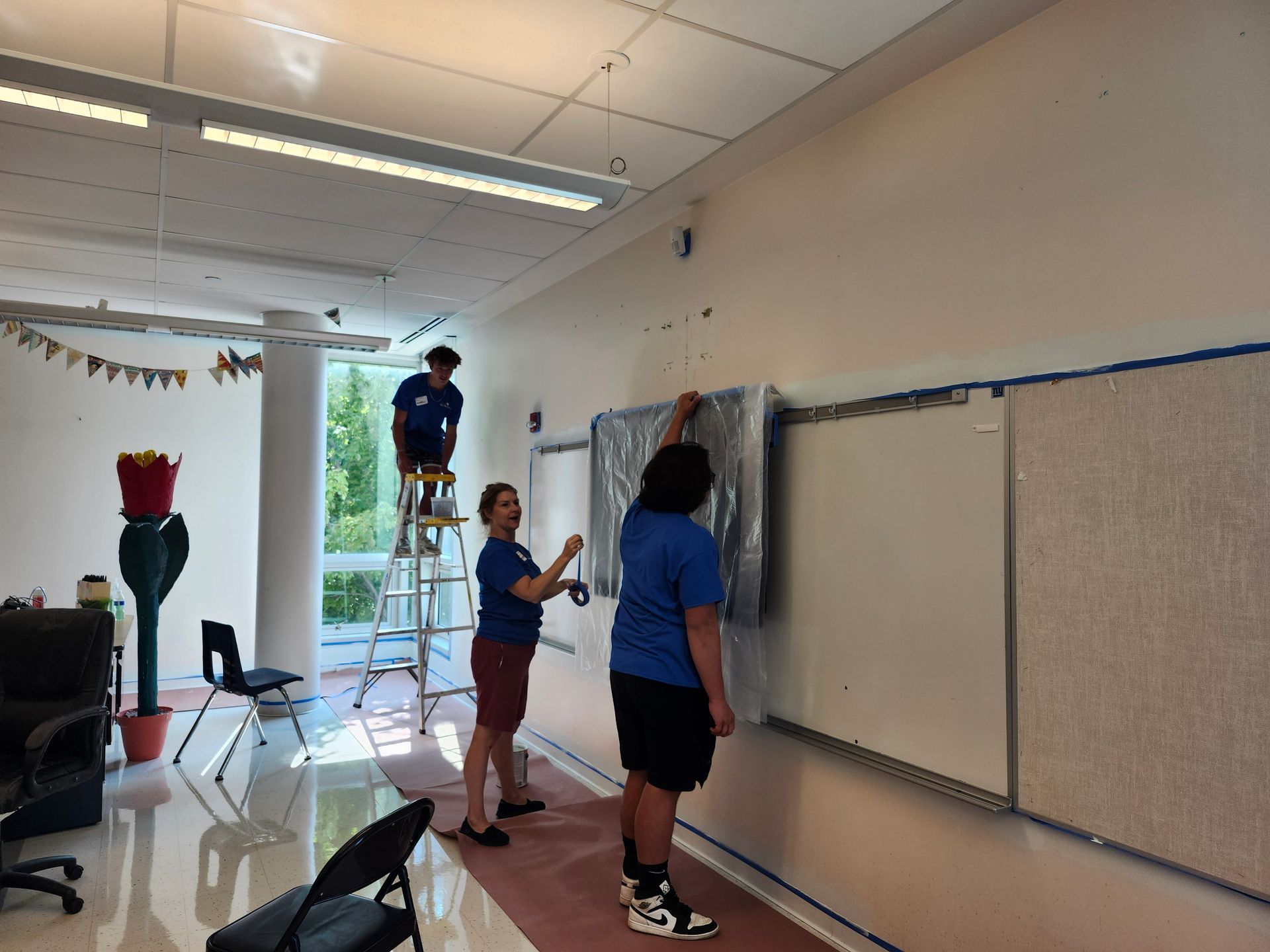 A group of people are working on a whiteboard in a classroom.