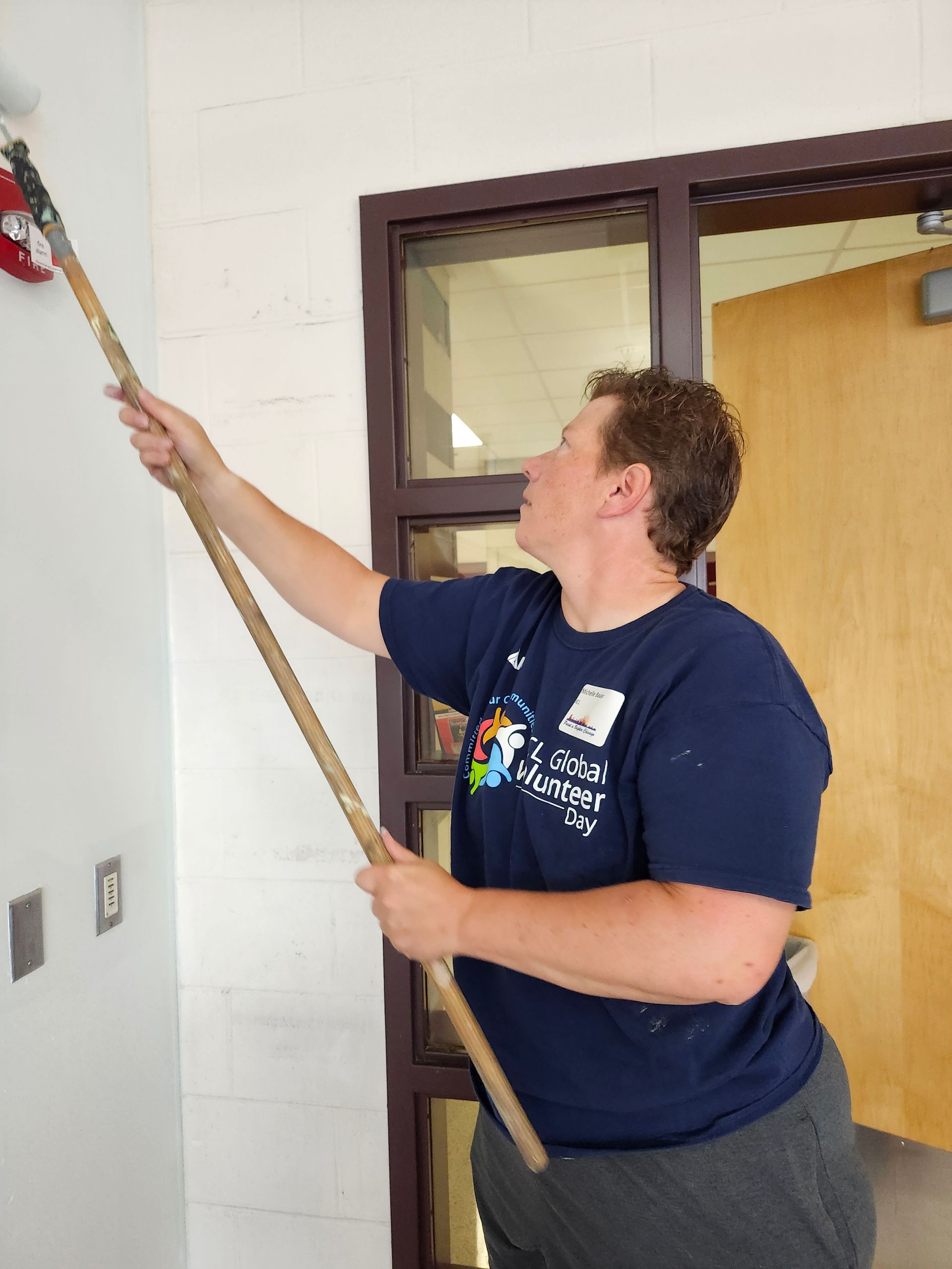 A man in a blue shirt is holding a paint roller
