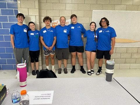 A group of people wearing blue shirts are posing for a picture.