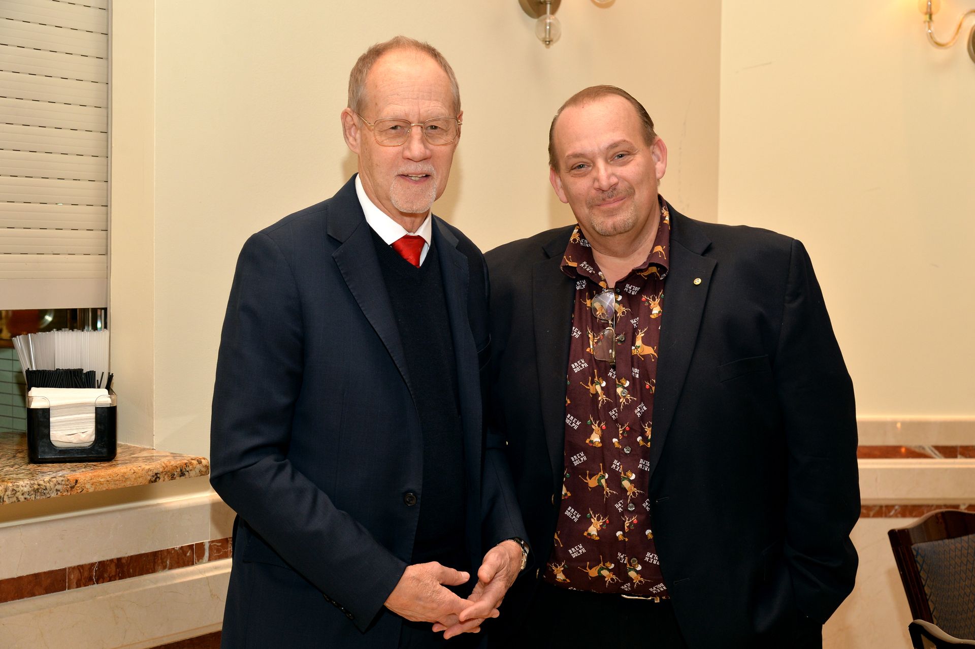 Two men in suits are standing next to each other in a room.