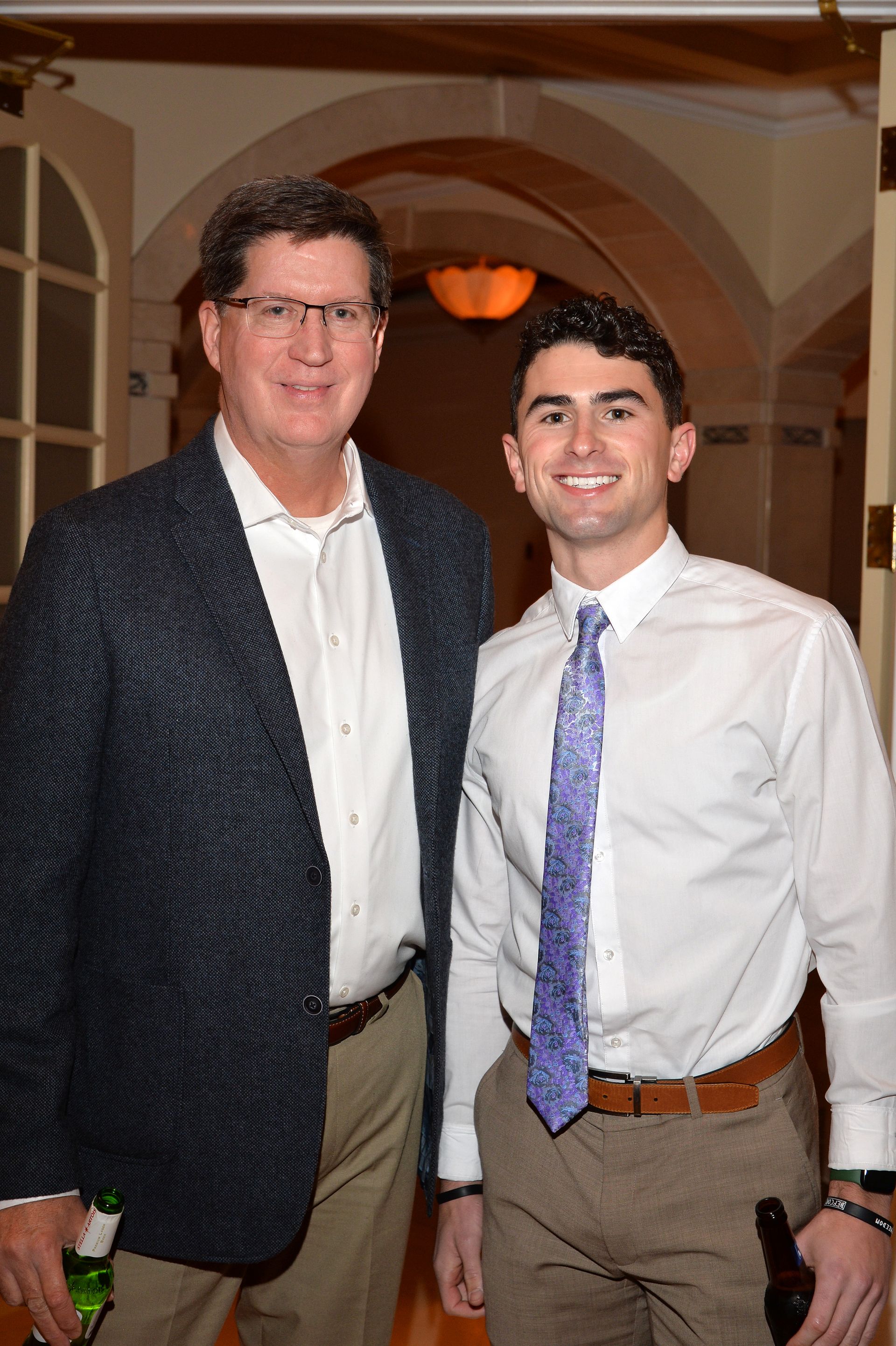 Two men are posing for a picture and one is wearing a purple tie