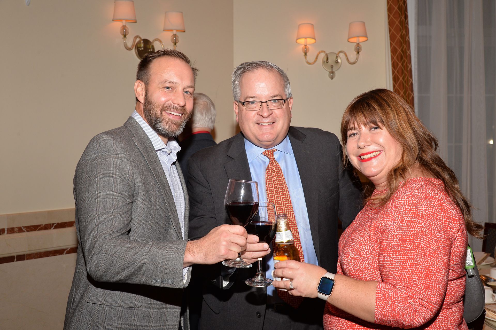 Three people are standing next to each other holding wine glasses.