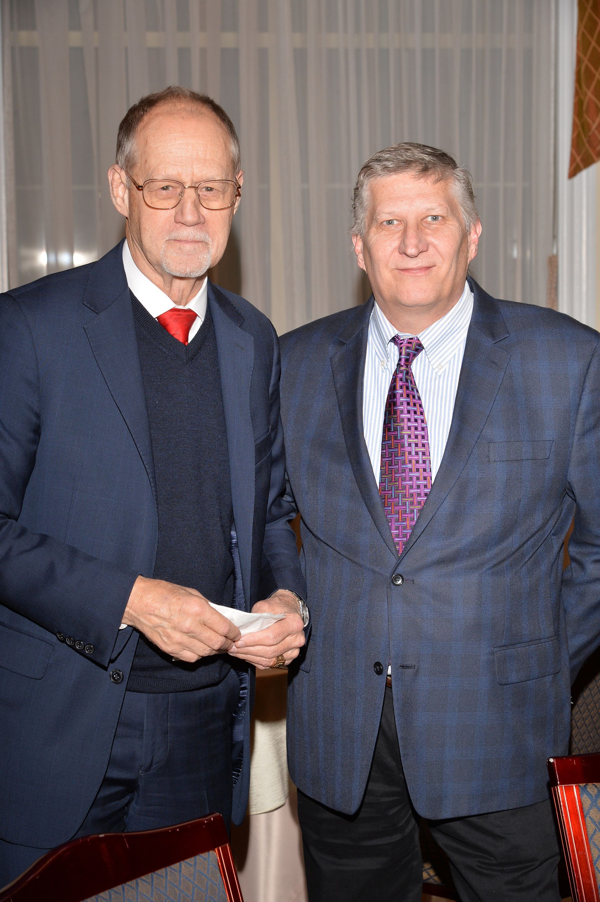 Two men in suits and ties are posing for a picture.