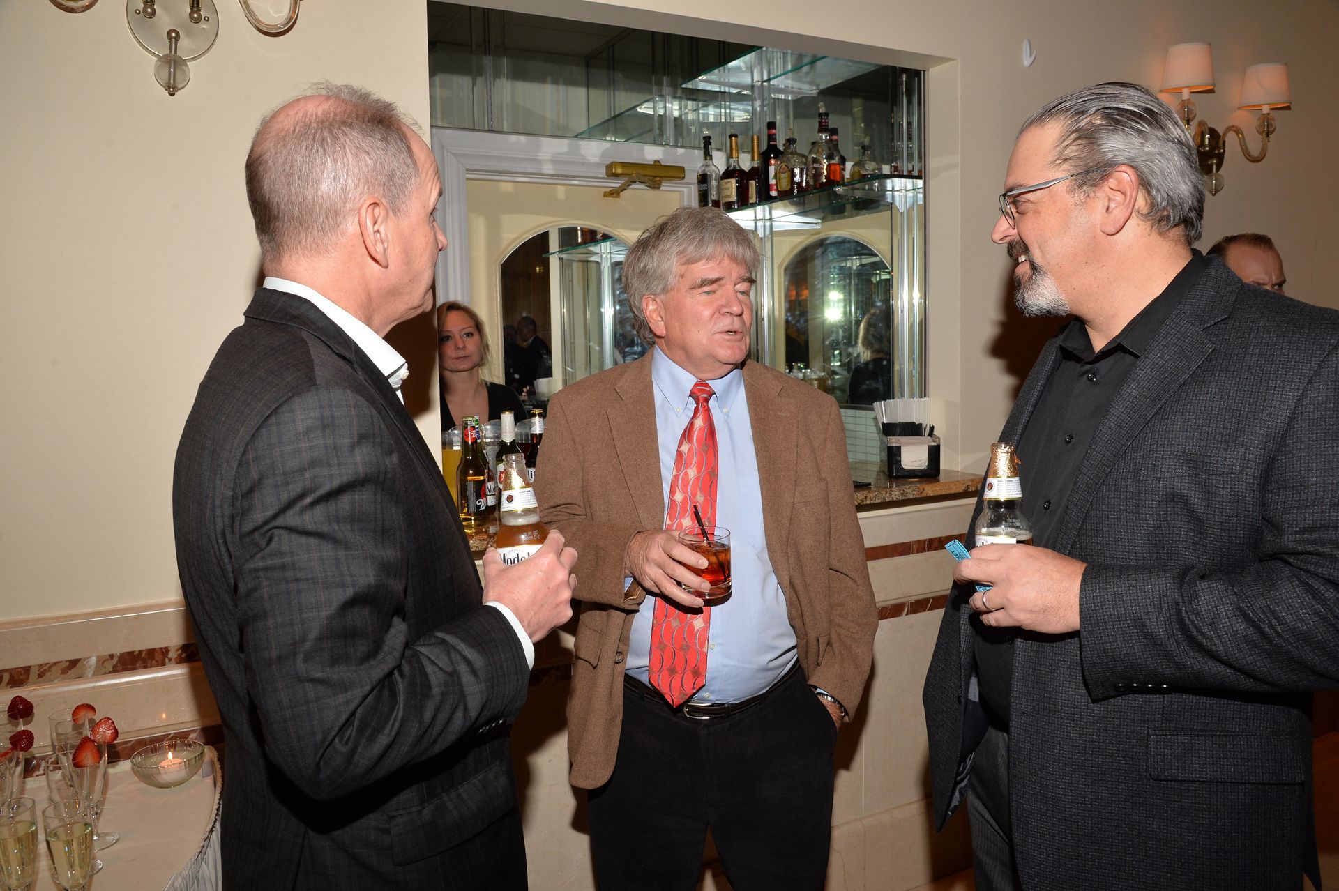 Three men are standing in a room talking to each other