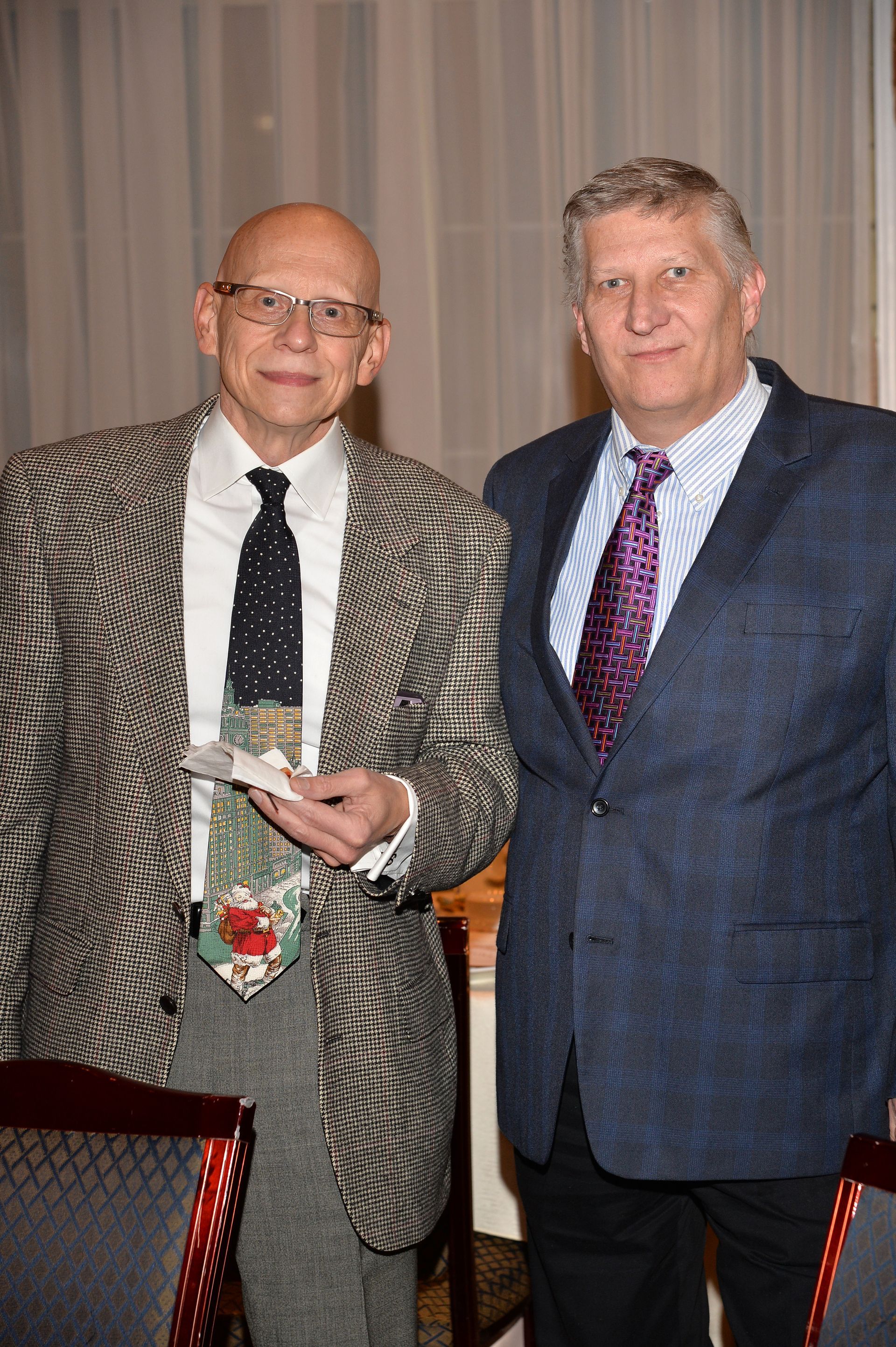 Two men in suits and ties are standing next to each other in a room.