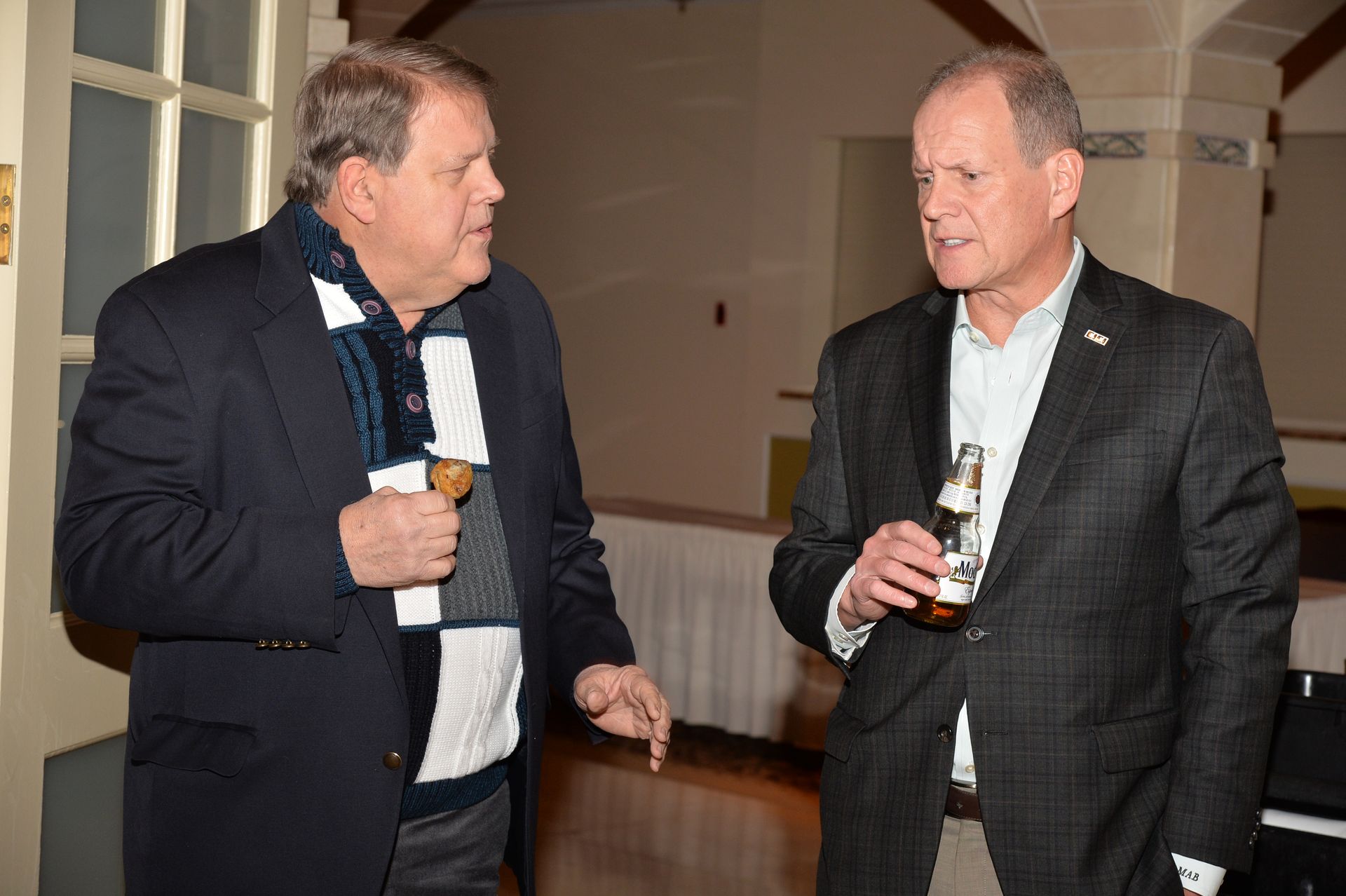 Two men in suits are talking to each other in a room.