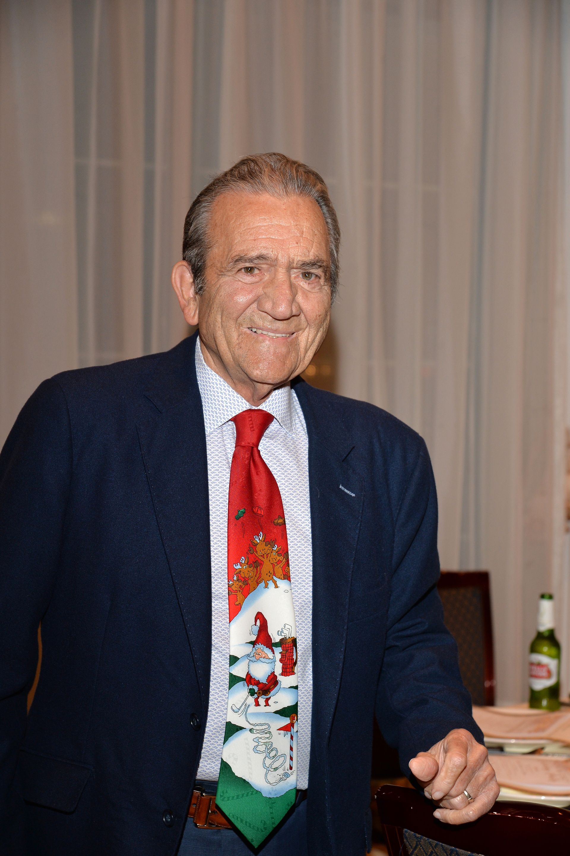 A man in a suit and tie is standing in front of a table.