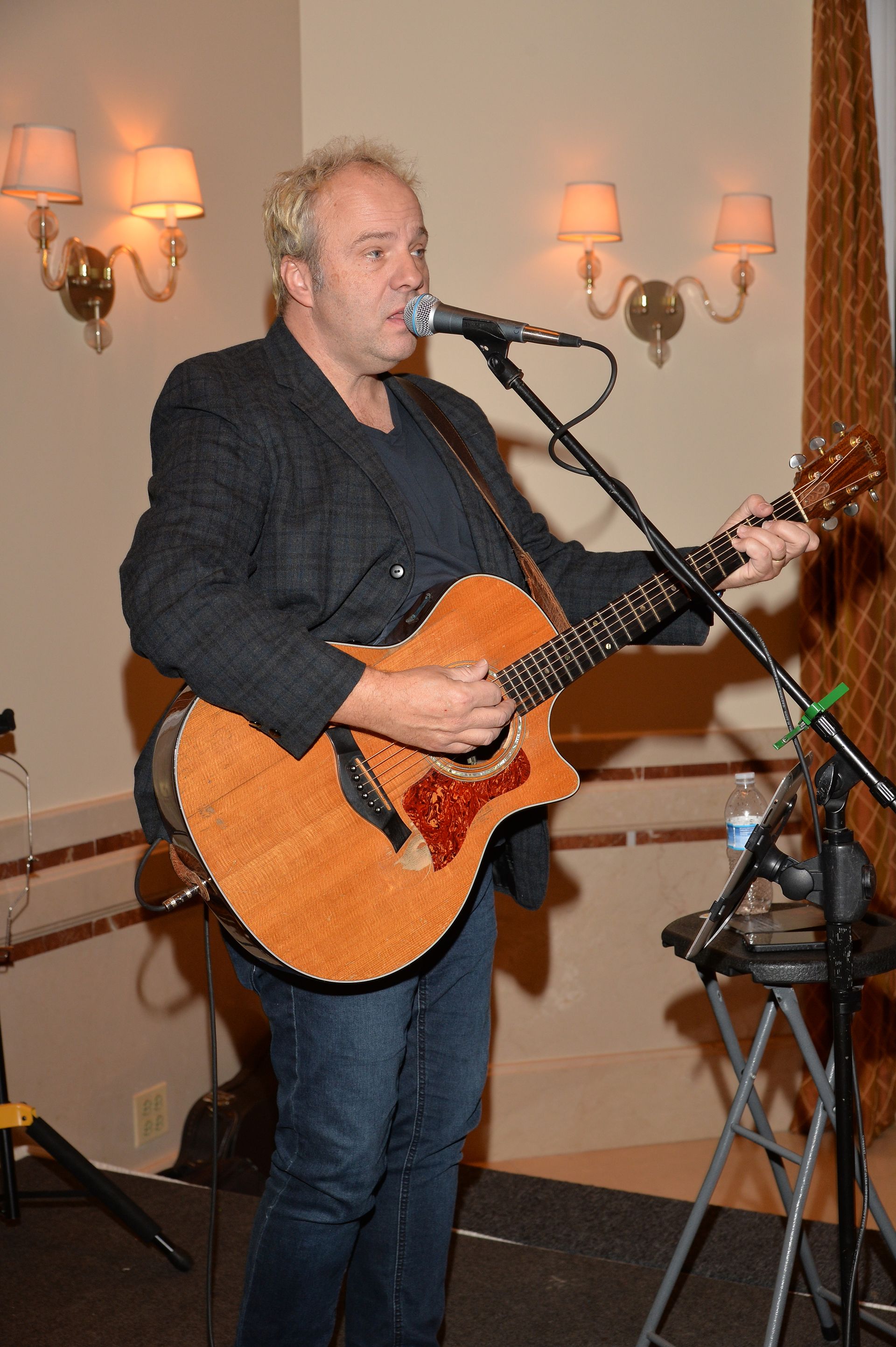A man is playing a guitar and singing into a microphone.