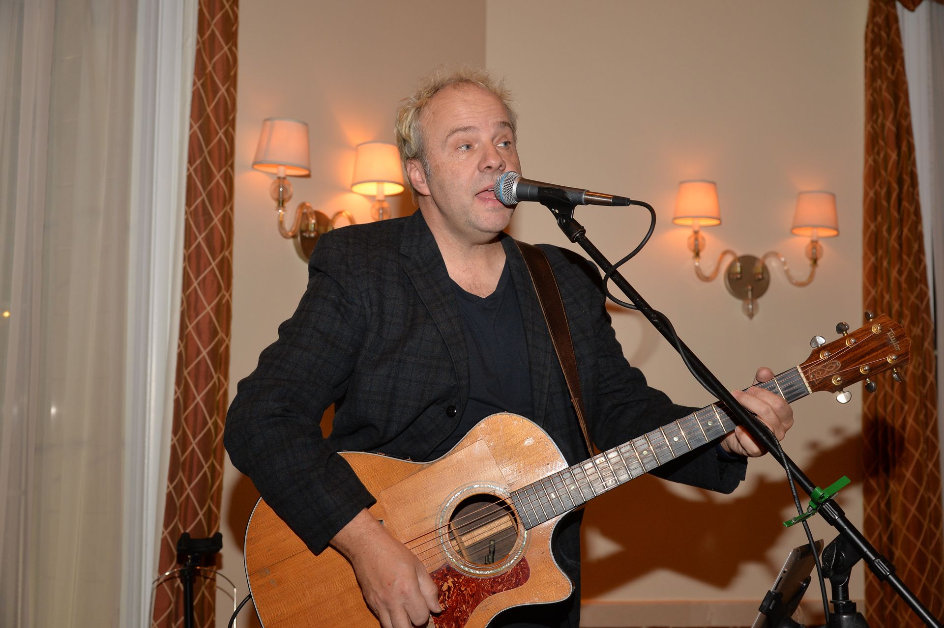 A man singing into a microphone while holding a guitar
