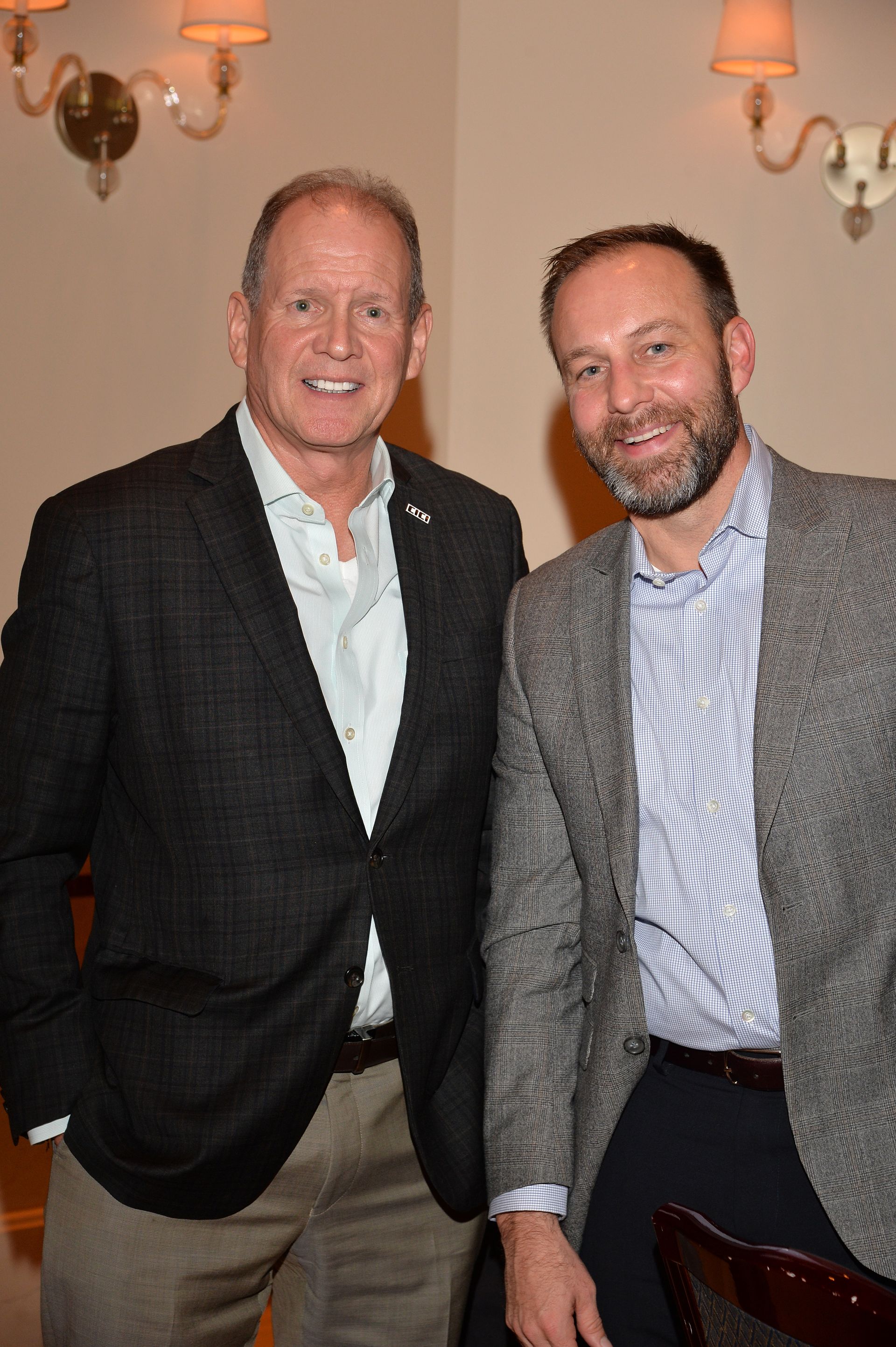 Two men in suits are posing for a picture in a room.