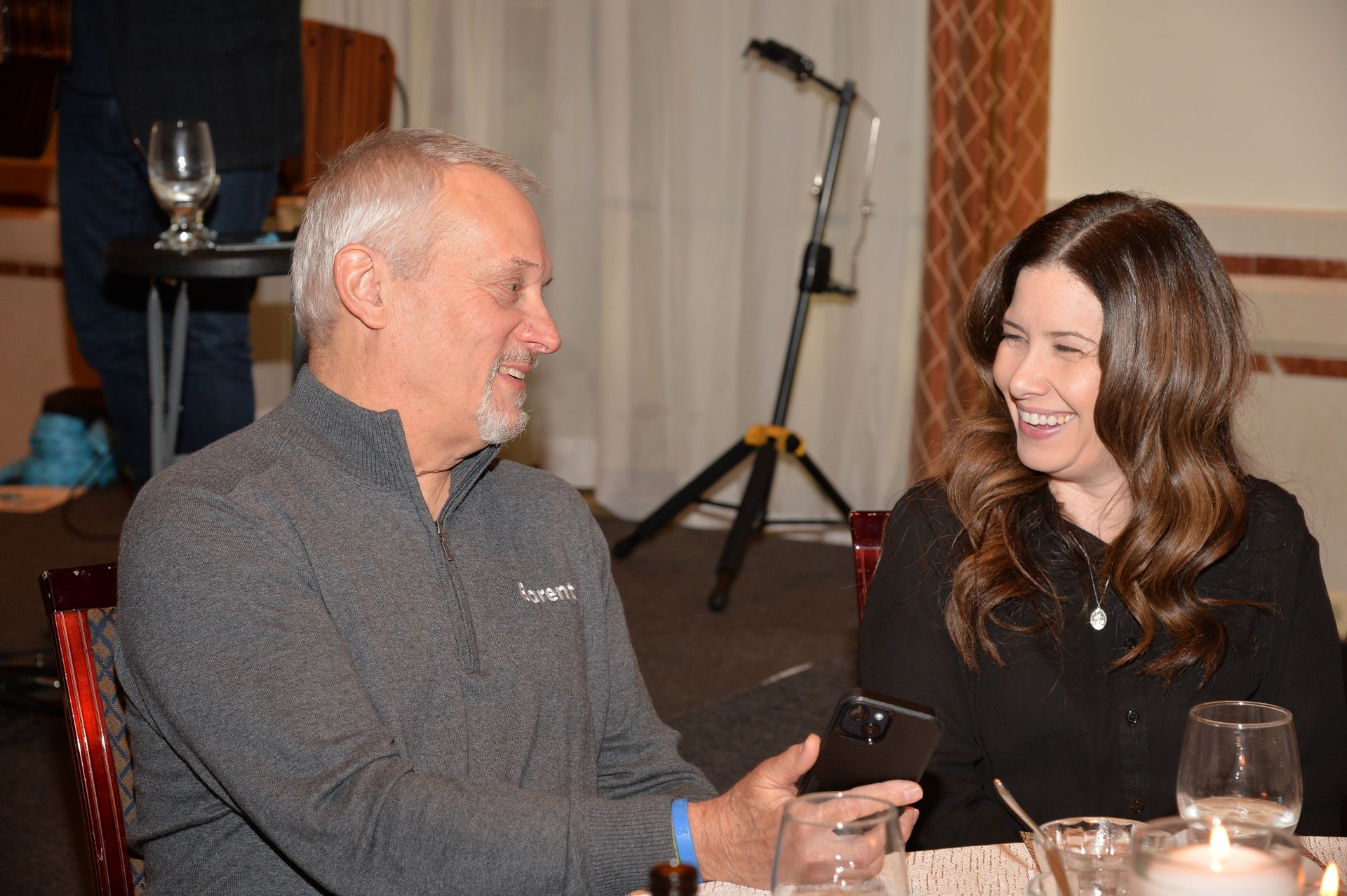 A man and a woman are sitting at a table talking to each other.