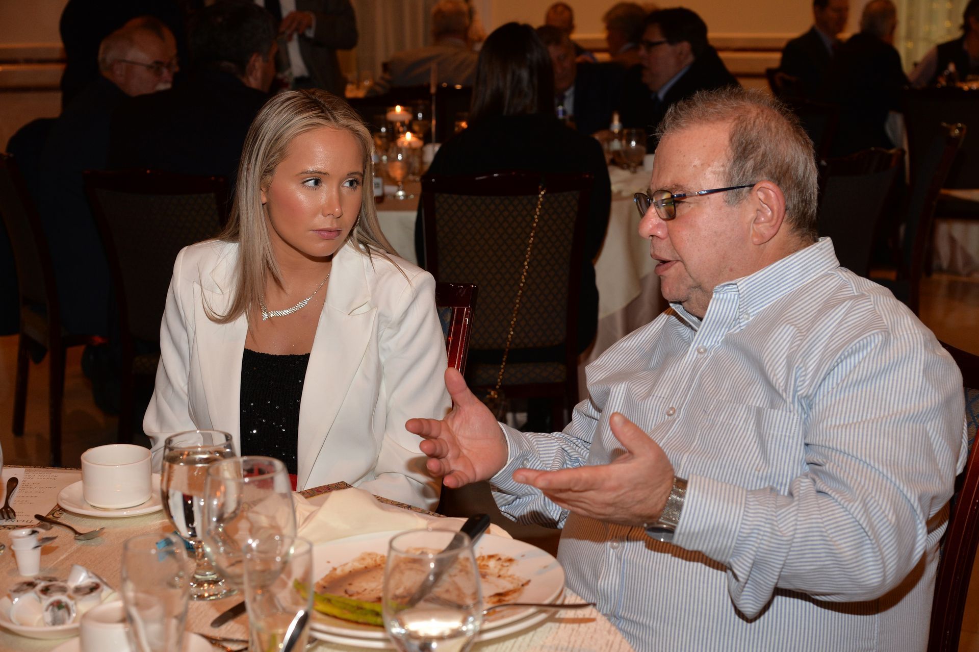 A man and a woman are sitting at a table talking to each other.