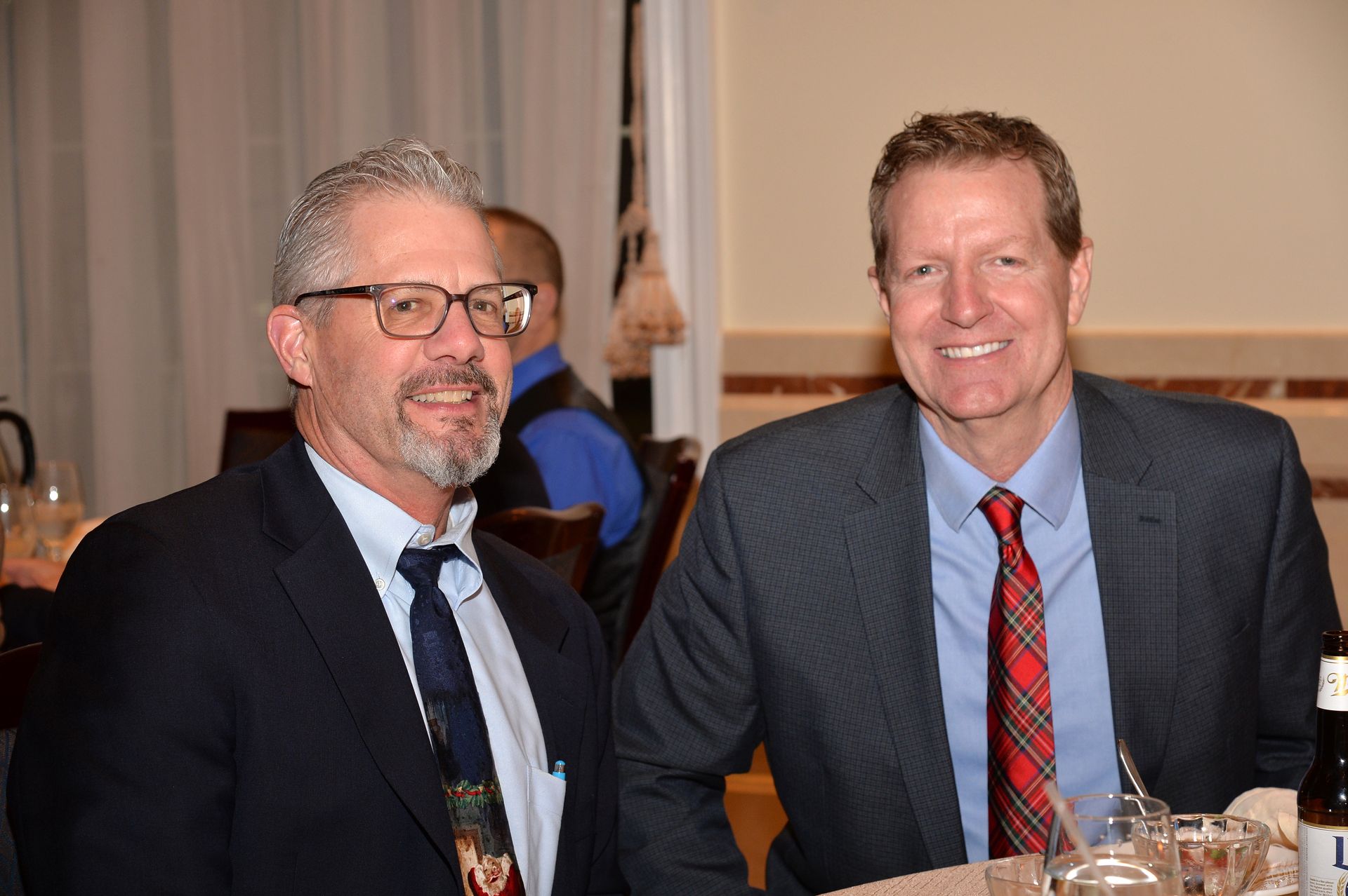 Two men in suits and ties are sitting at a table.