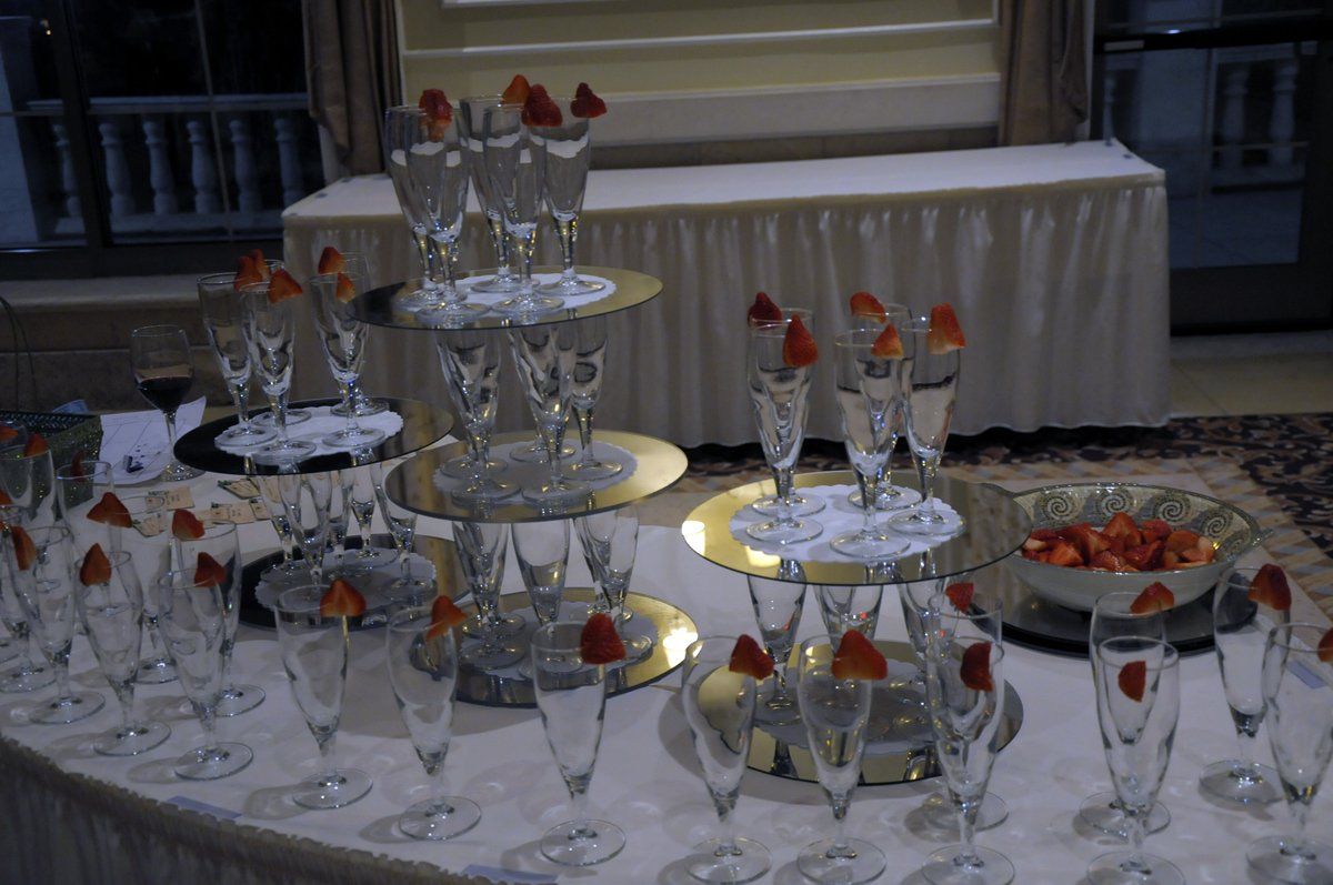 A table with a lot of wine glasses and strawberries on it