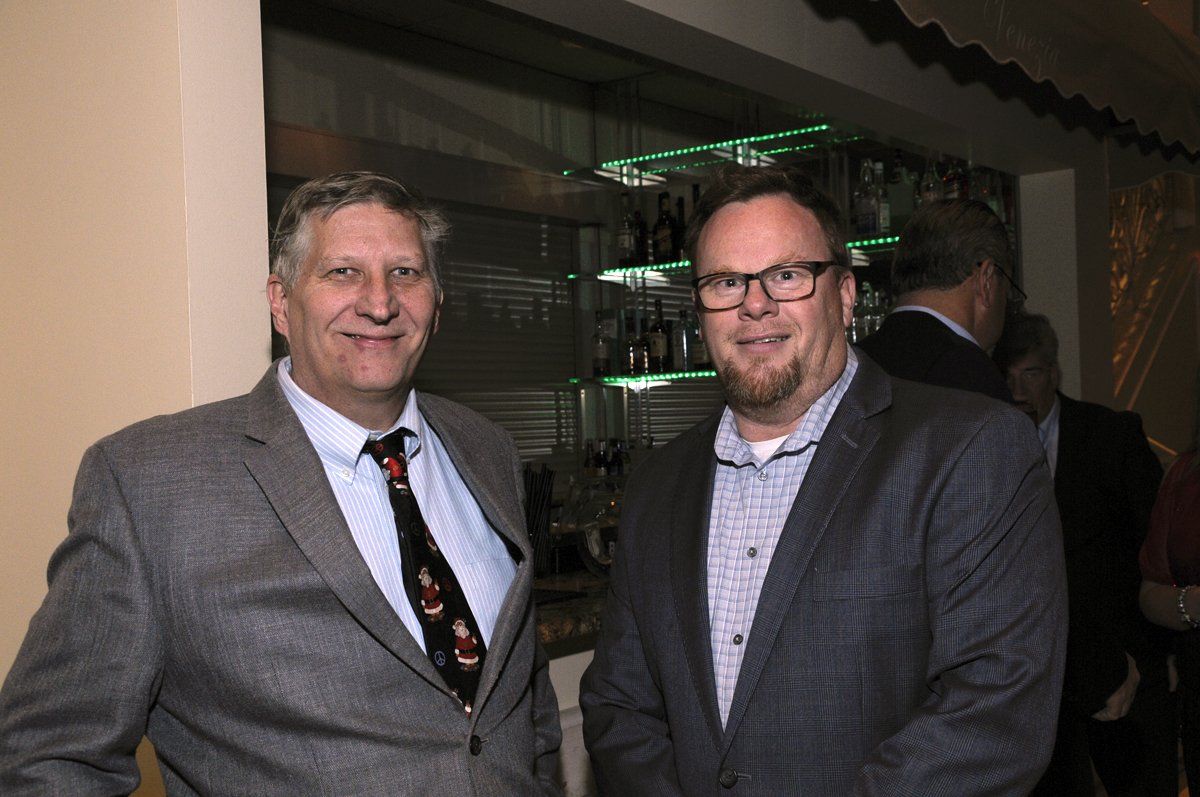 Two men in suits and ties are standing next to each other in a room.