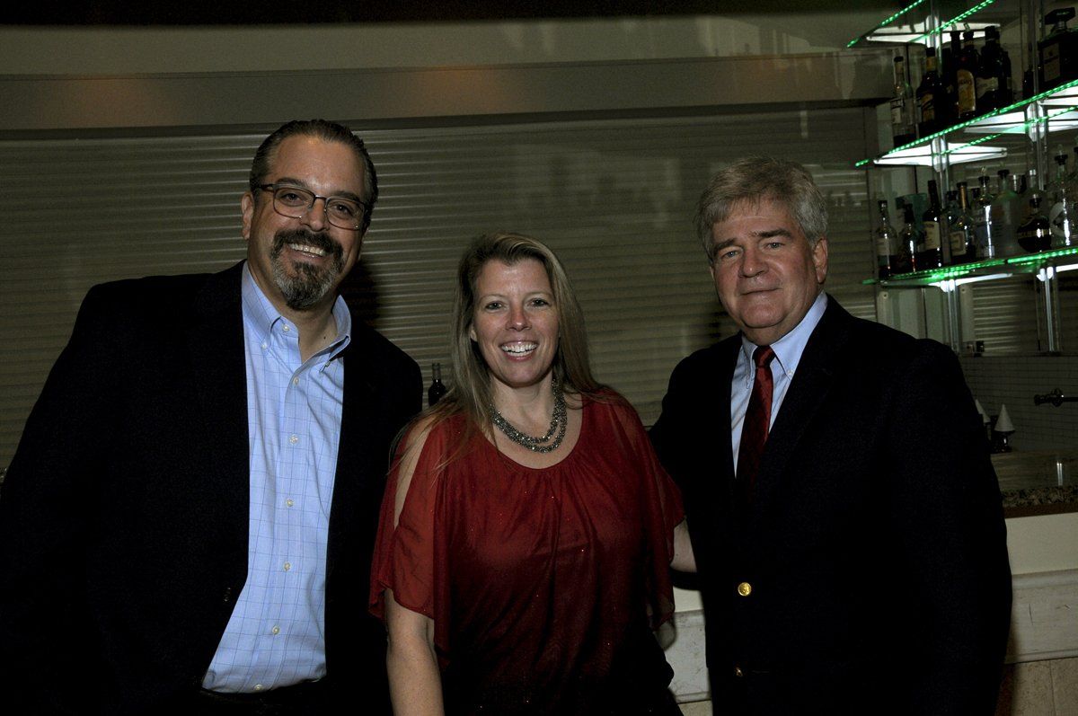 Three people are posing for a picture in front of a bar.