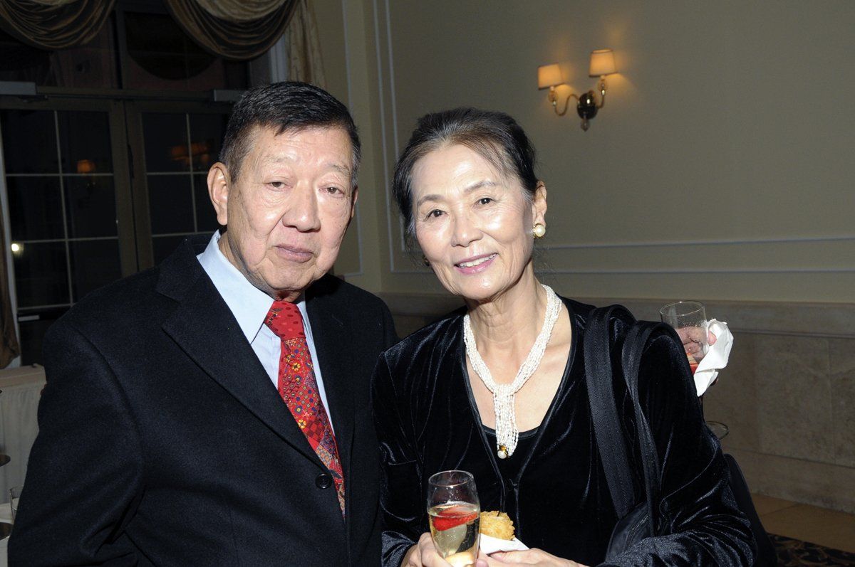 A man and a woman are posing for a picture while holding champagne glasses.