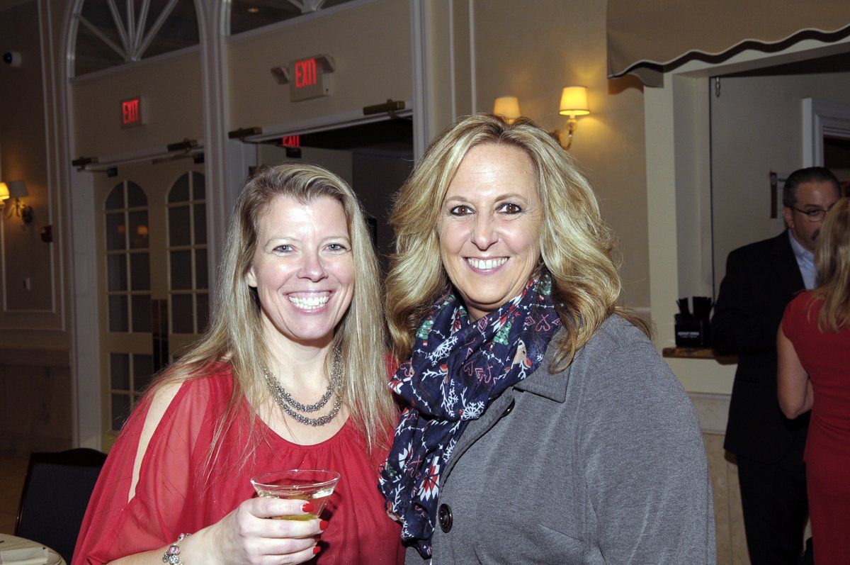 Two women are posing for a picture while holding drinks.