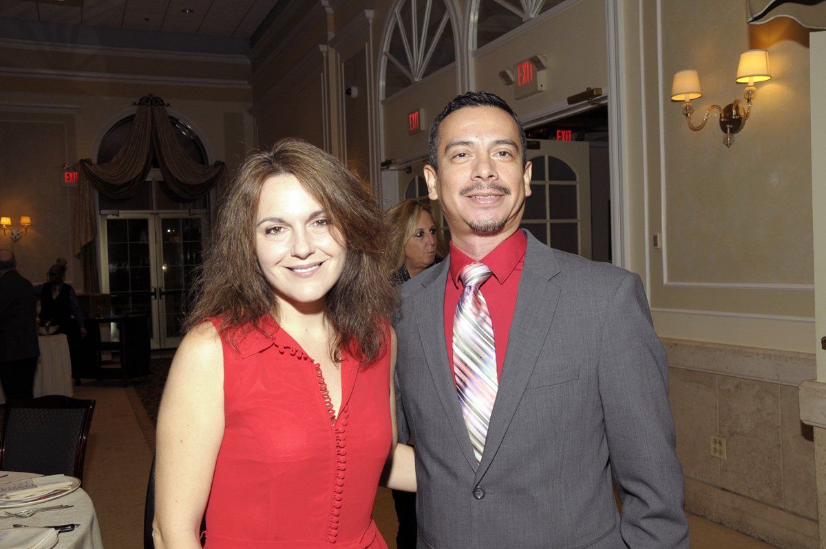 A man in a suit and tie poses with a woman in a red dress