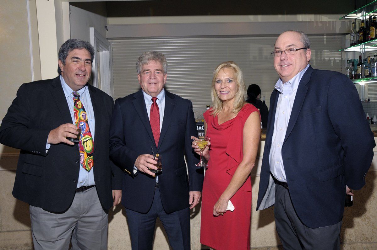 A woman in a red dress is standing between two men in suits