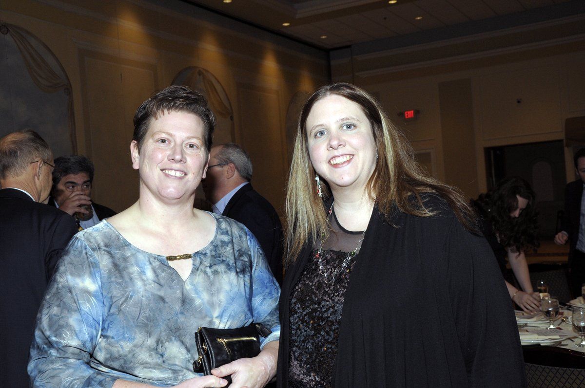 Two women are standing next to each other and smiling for the camera