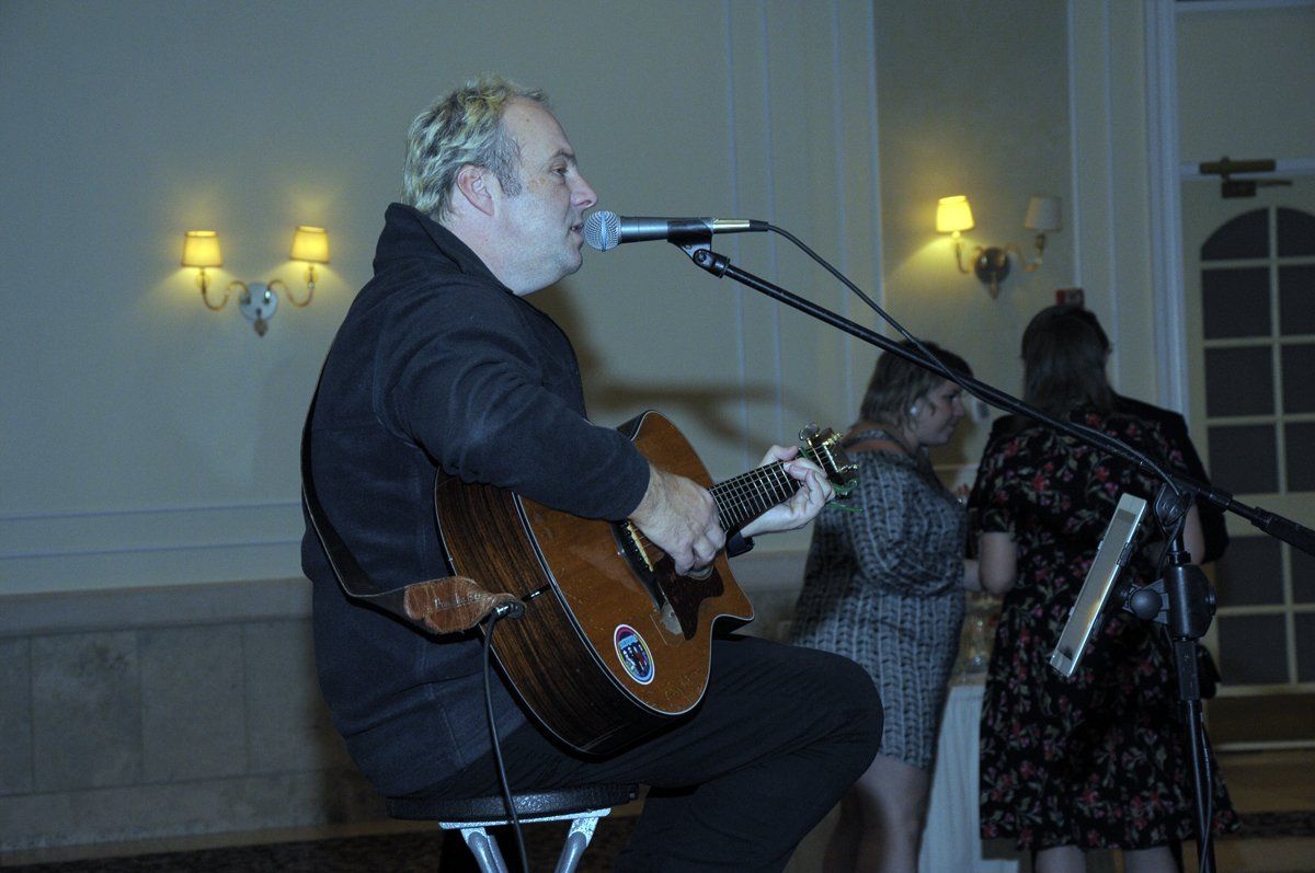 A man is singing into a microphone while playing a guitar.