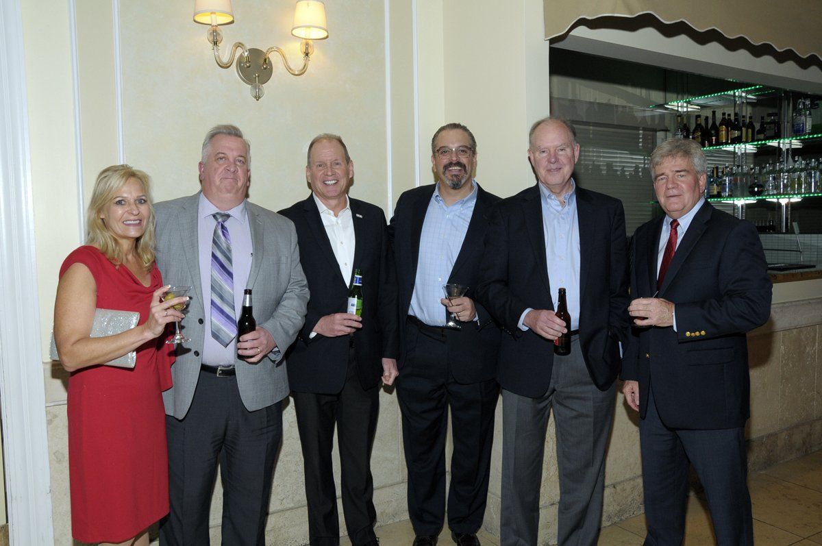 A group of people standing next to each other holding bottles of beer.