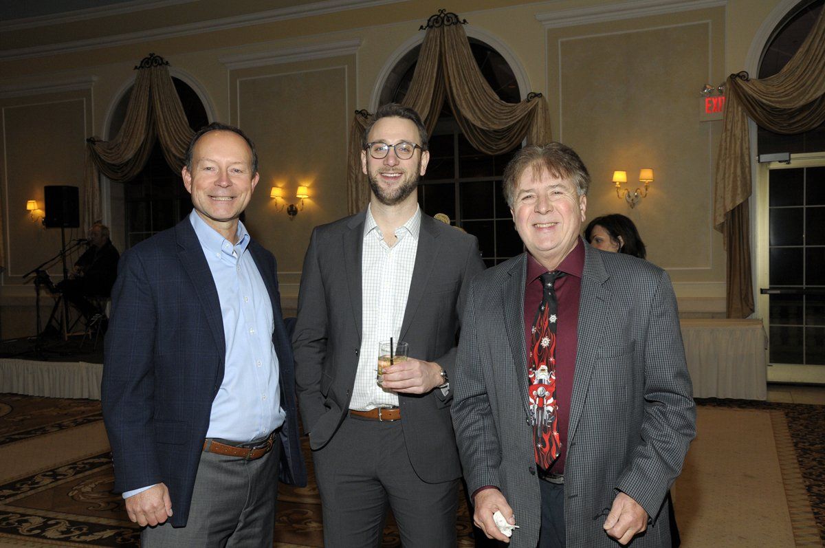 Three men in suits are posing for a picture in a room.