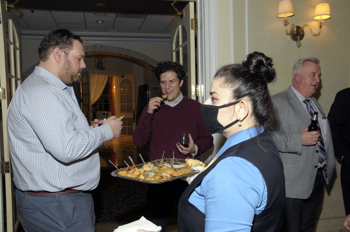 A woman wearing a mask is serving food to a group of people.