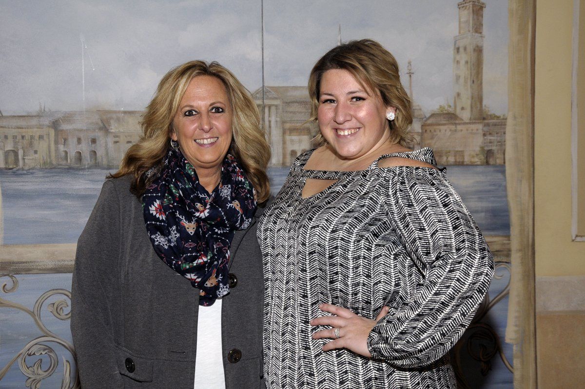 Two women are posing for a picture in front of a painting.