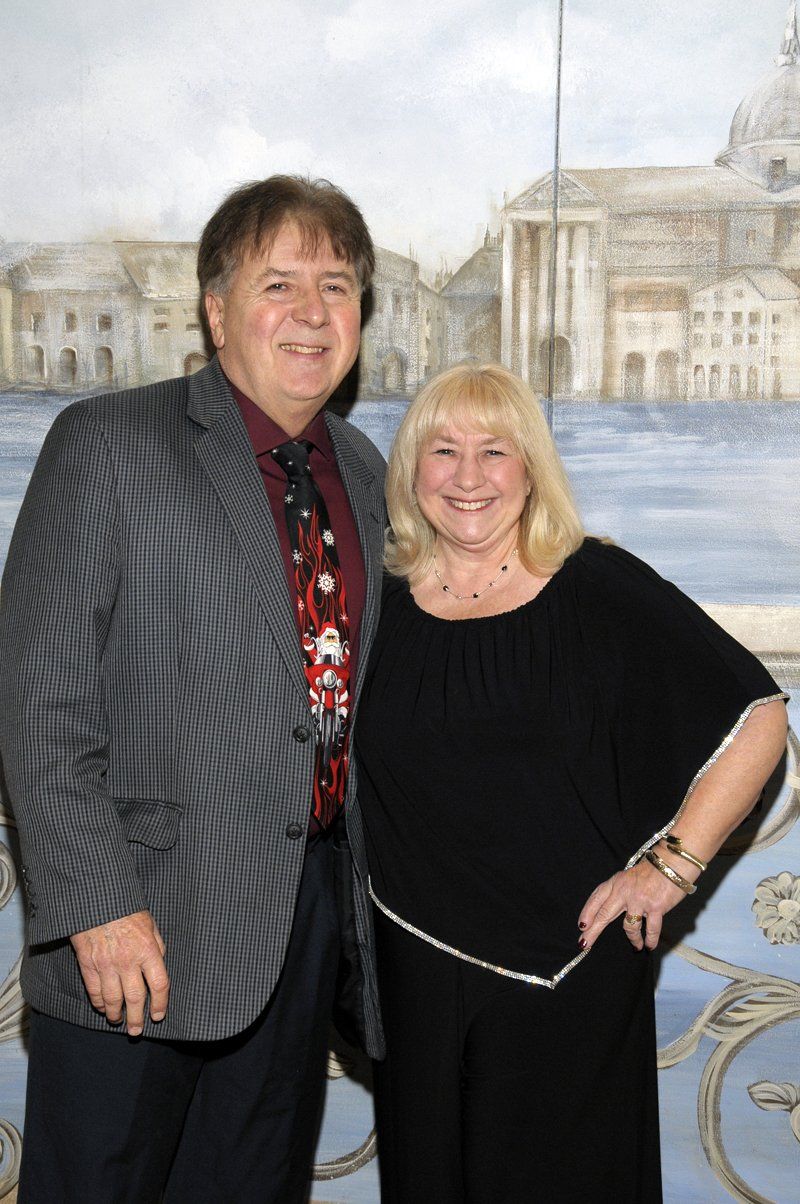 A man and a woman are posing for a picture in front of a painting