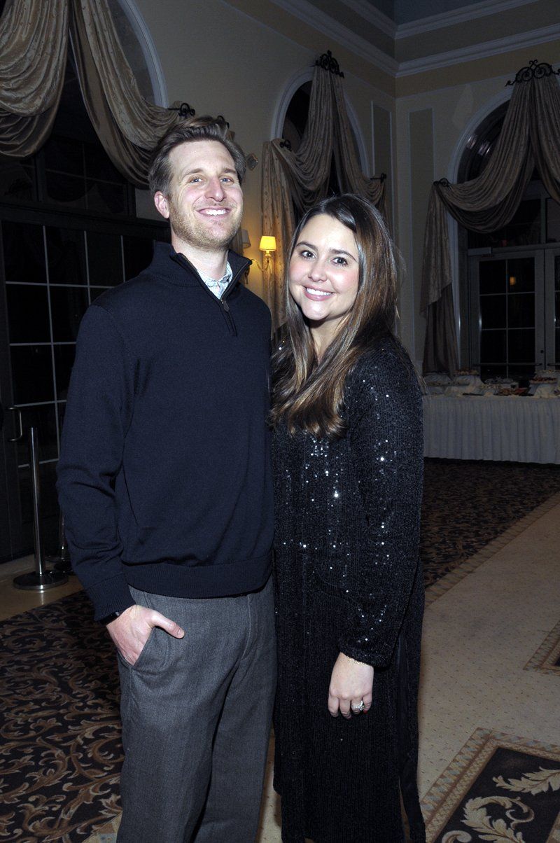 A man and a woman are posing for a picture in a room