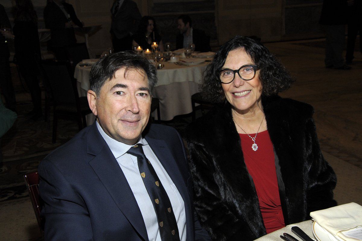 A man and a woman are sitting at a table at a party.