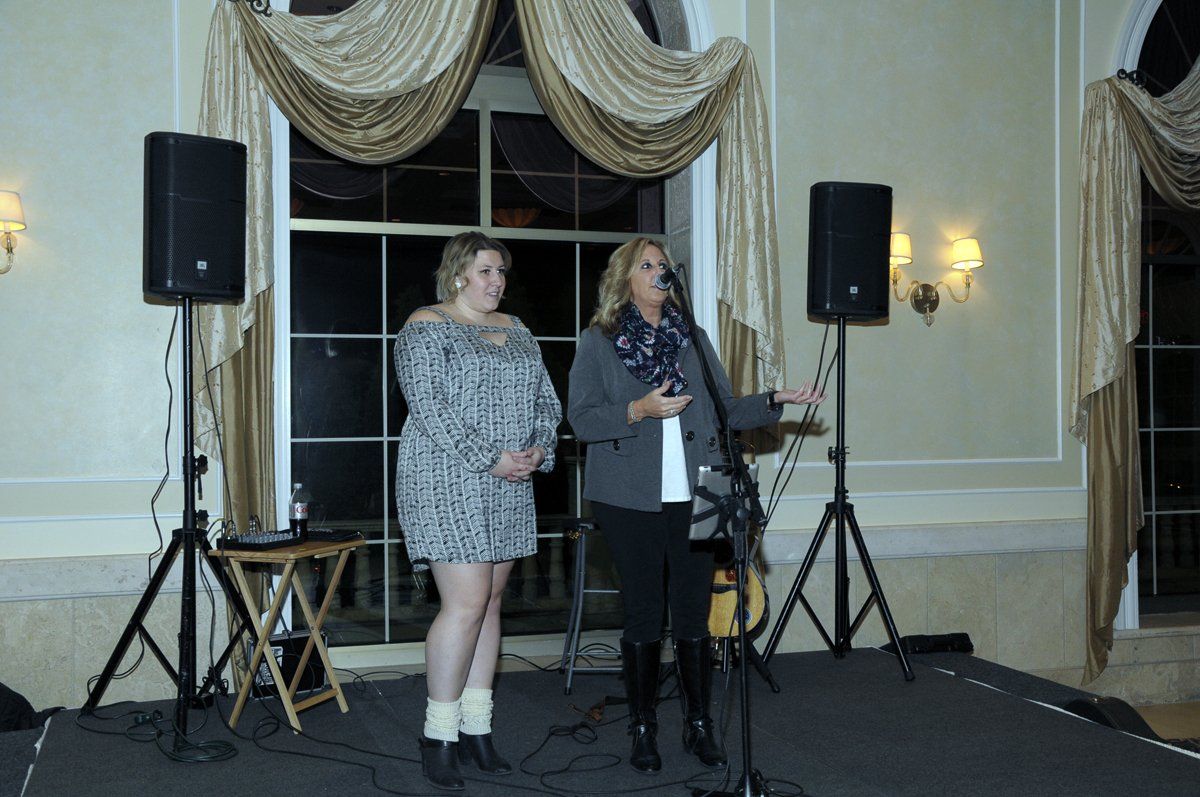 Two women are standing in front of a microphone in a room.