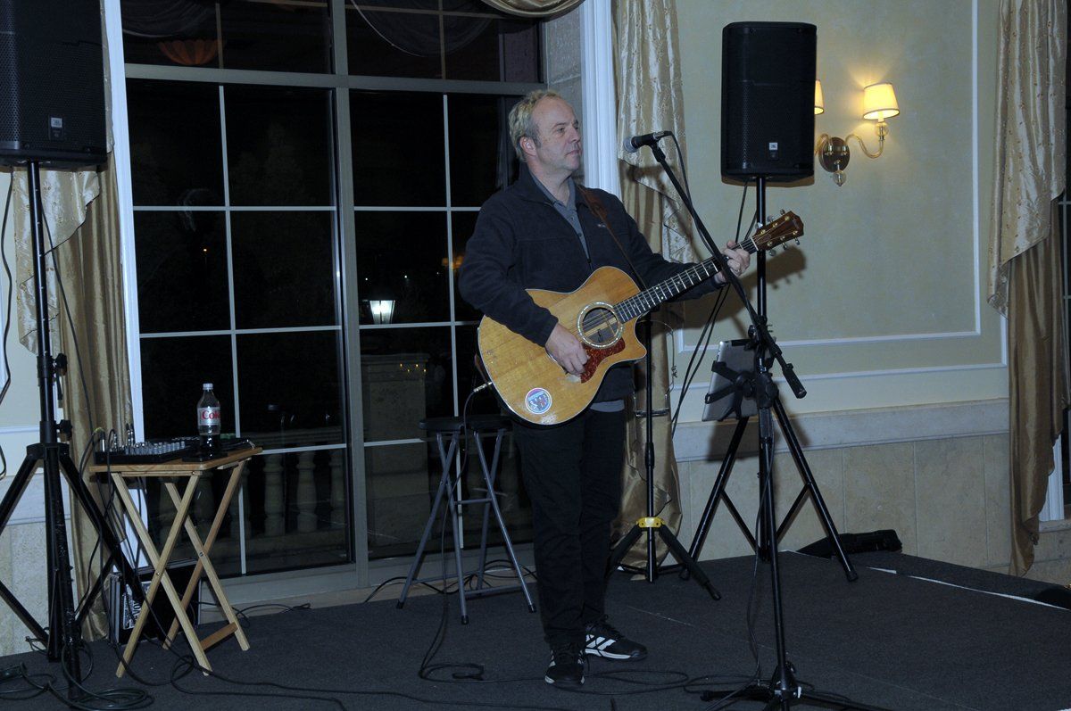A man is playing a guitar and singing into a microphone