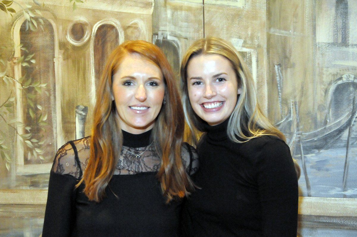 Two women are posing for a picture in front of a painting.