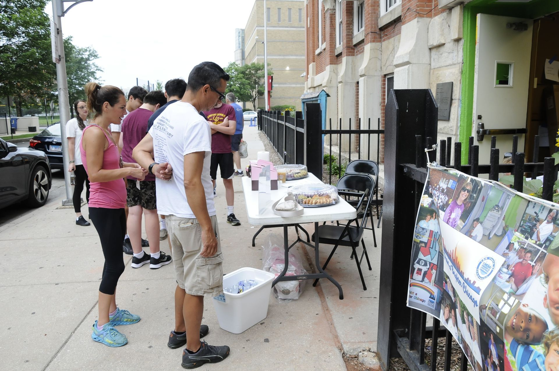 A group of people standing around a table on the sidewalk